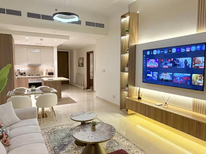 Living room with large TV wall, dining table and open kitchen