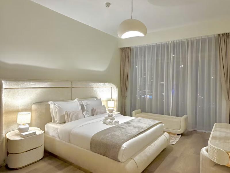 Main bedroom with upholstered headboard and sheer curtains